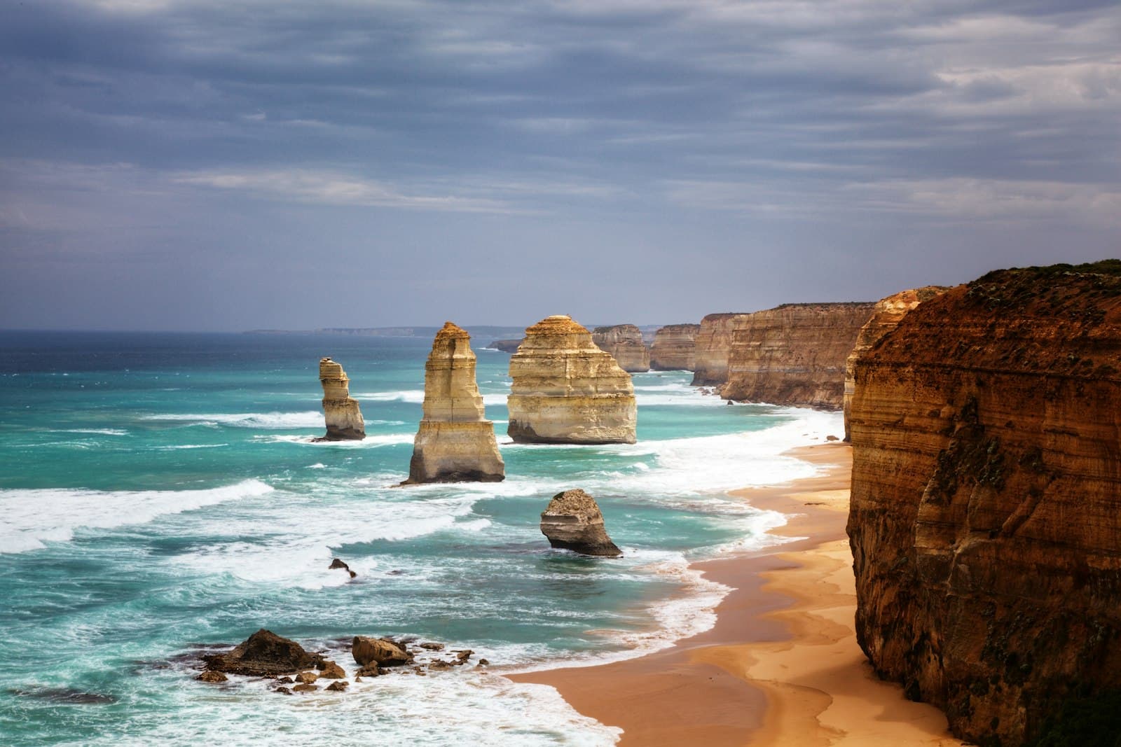 The Twelve Apostles rock stacks rising from the surf beside golden cliffs