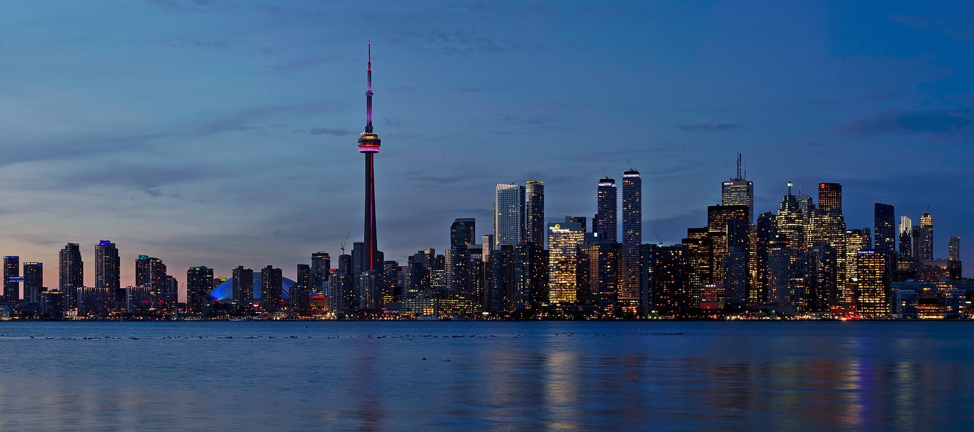 Toronto's skyline and the CN Tower at dusk across the harbour