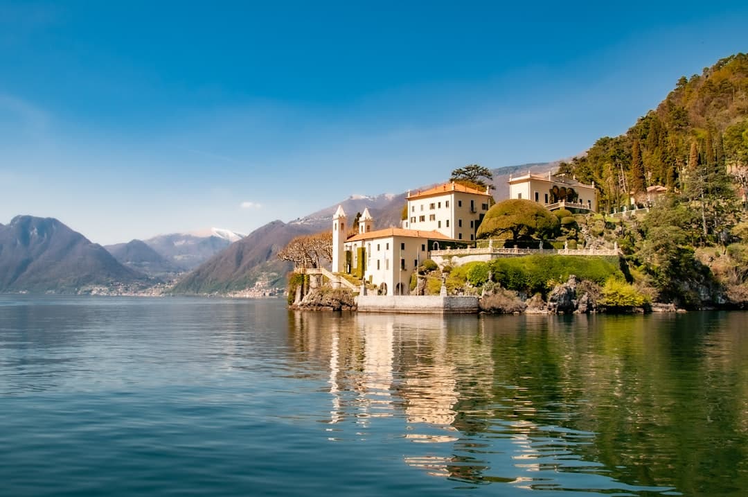 A lakeside villa on a wooded promontory reflected in Lake Como