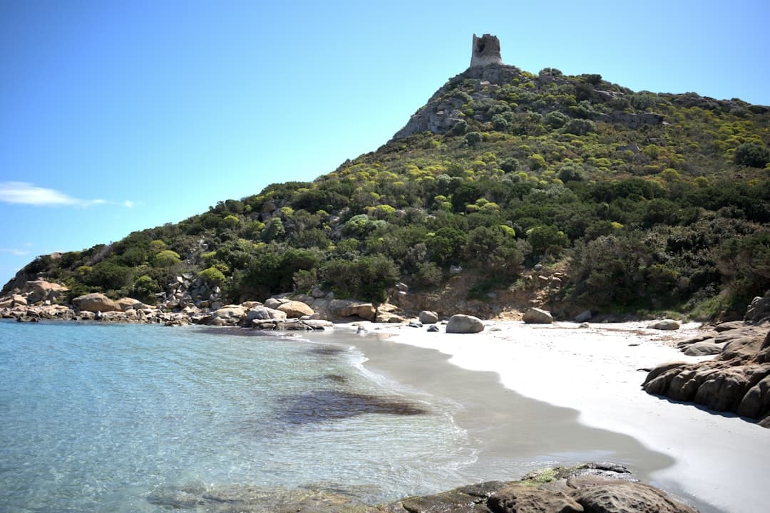A white-sand Sardinian cove beneath a watchtower-topped headland