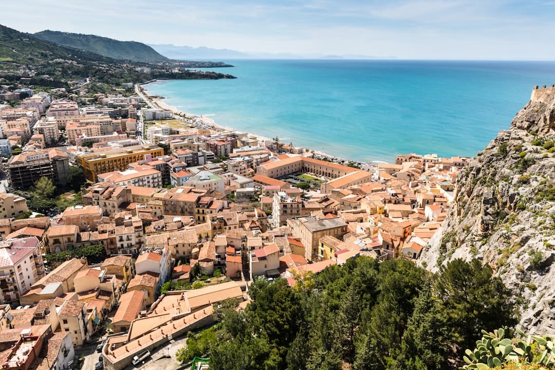 Cefalù's terracotta rooftops curving along the beach and turquoise sea