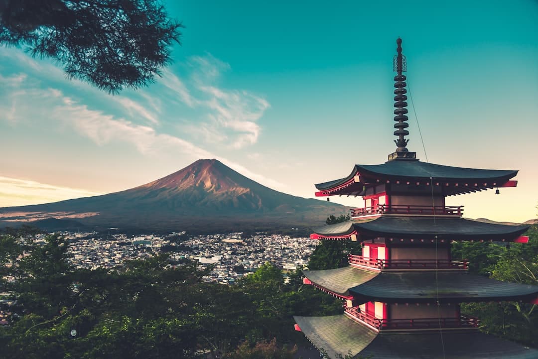 Mount Fuji rising snow-capped beyond a lakeside pagoda