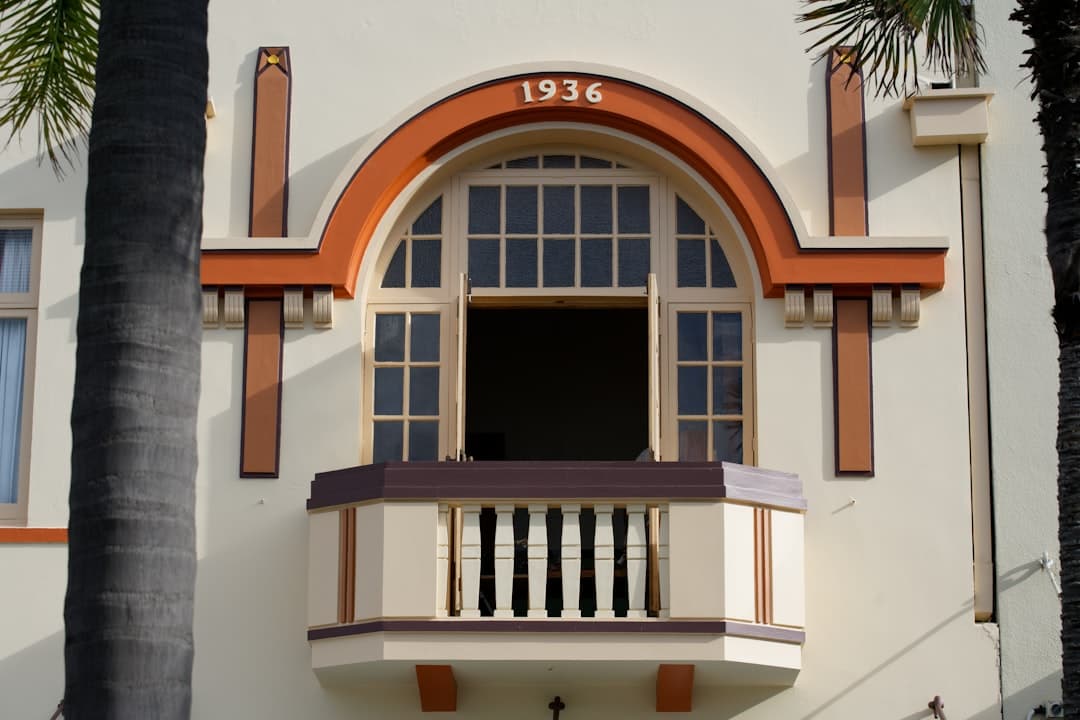 An ornate 1936 art-deco facade framed by palm trunks in Napier
