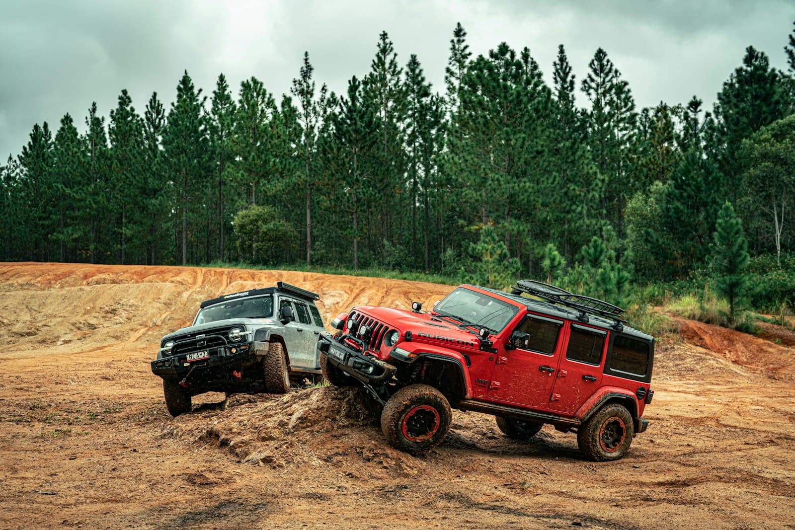 Two four-wheel drives climbing a red-dirt track
