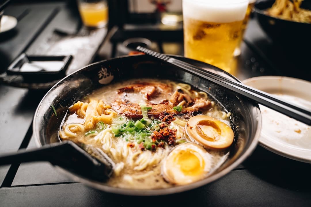 A steaming bowl of ramen with chopsticks lifting noodles