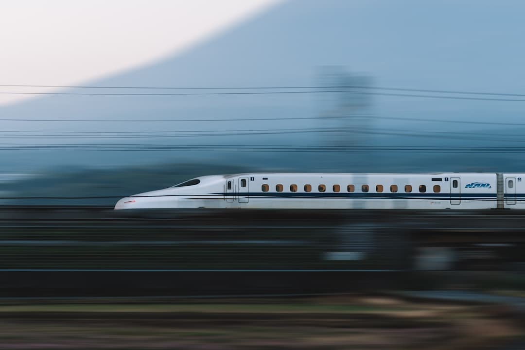 A shinkansen streaking past at speed, mountains blurred behind