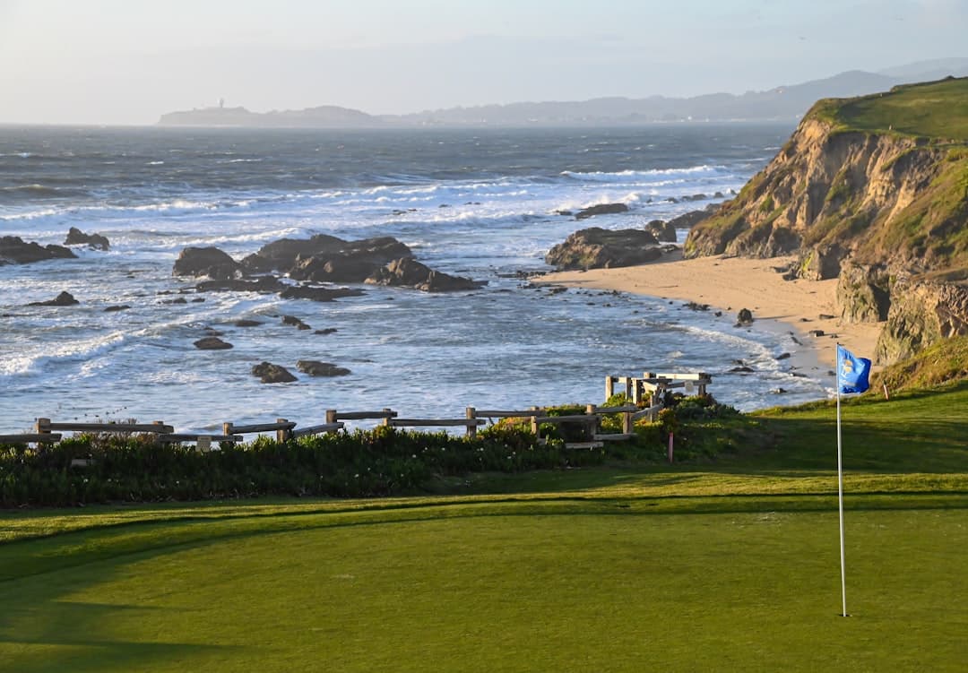 A links golf course running along low coastal cliffs beside a surf beach