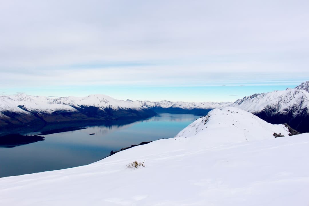A snow-covered ridge in the Remarkables above the dark waters of Lake Wakatipu
