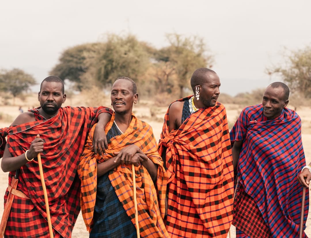 Maasai warriors in red shúkàs against the savannah