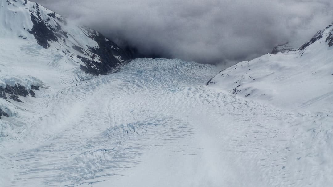 The crevassed ice of Franz Josef Glacier with cloud spilling over the valley