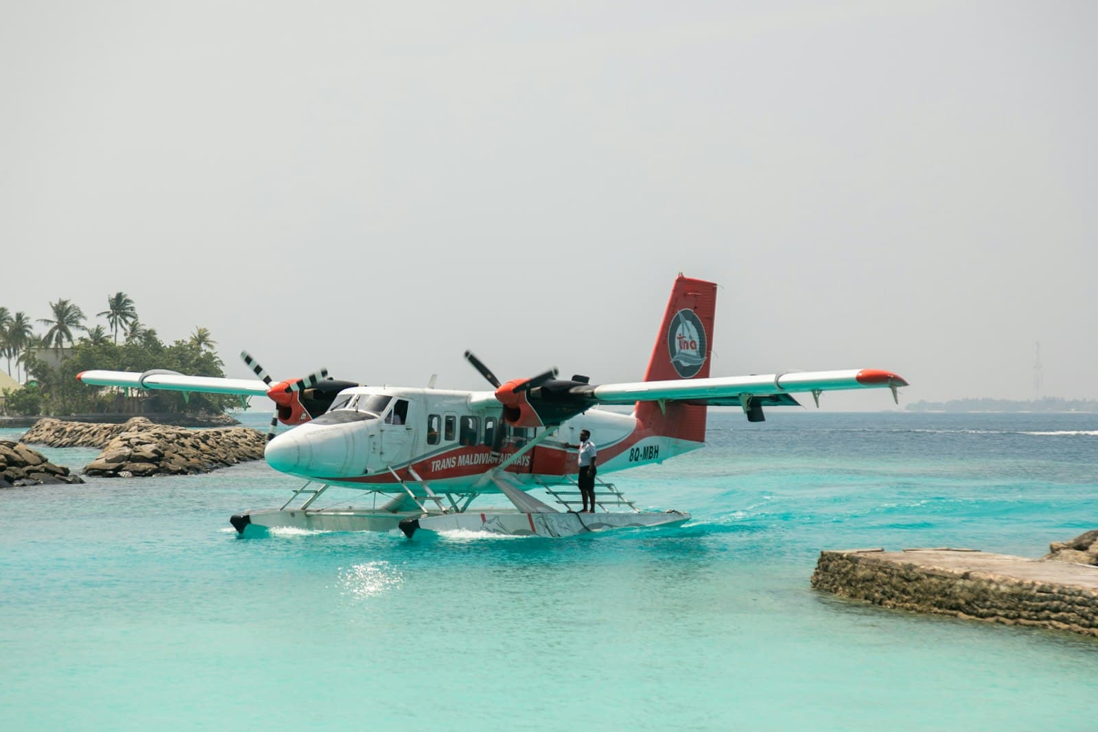 A seaplane taxiing across turquoise water between islands