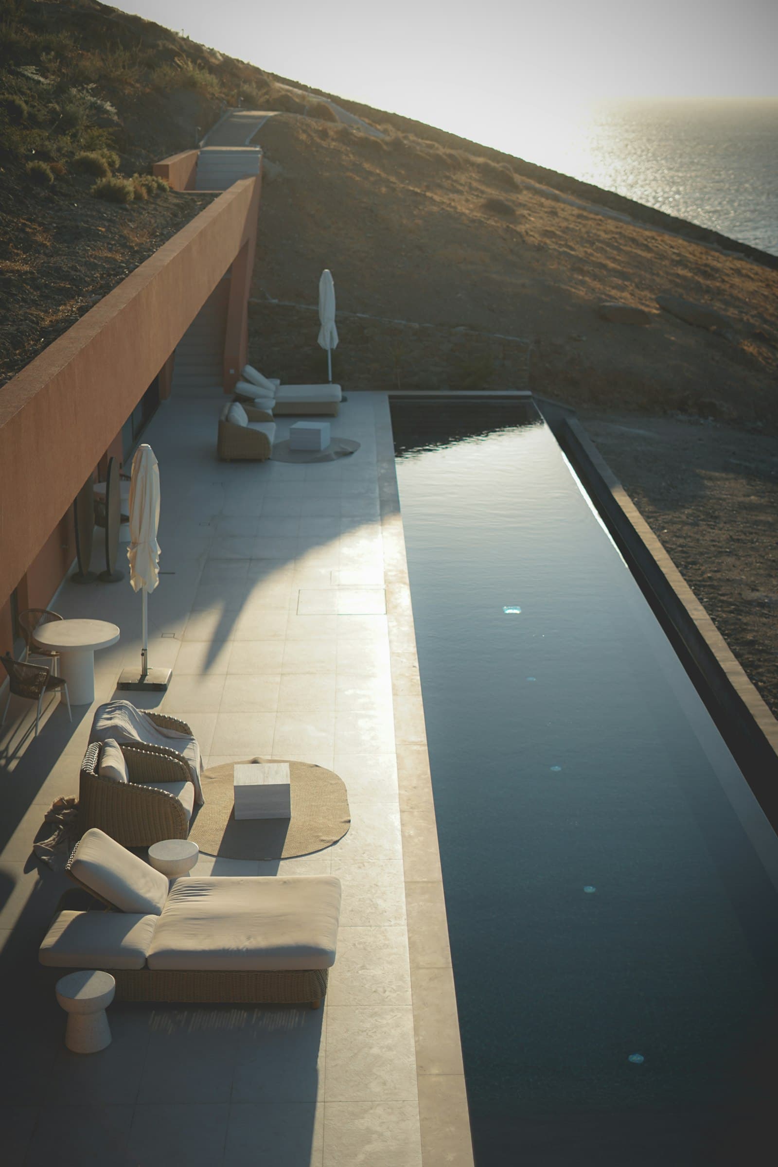 A terracotta villa's infinity pool at golden hour above the sea